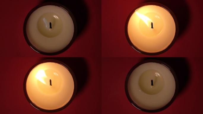 燃烧蜡烛的俯视图在深红色背景上关闭。慢动作全高清视频。蜡烛火焰特写。蜡烛打开了，蜡烛吹灭了
