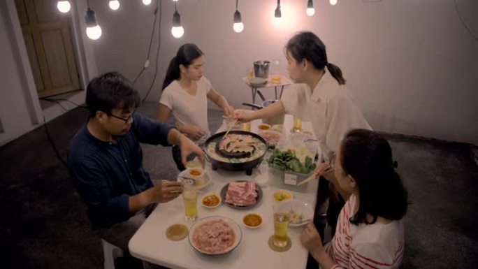 亚洲家庭吃泰国菜流行风格的派对，泰语中的 “猪肉锅” 正在将猪肉放在锅中烤