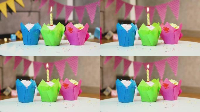 多色节日松饼的特写镜头，配有燃烧的蜡烛和花环。任何年龄的生日快乐背景