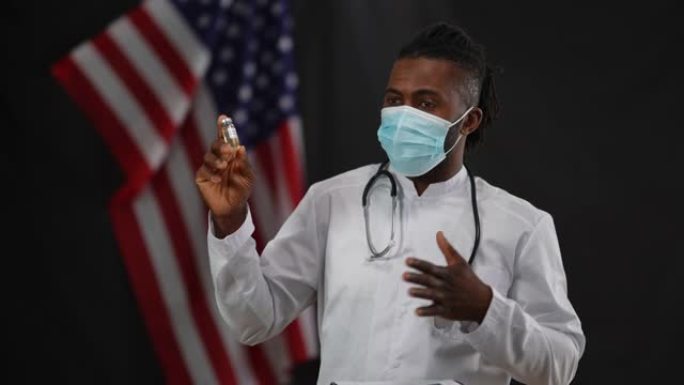 非裔美国男性科学家在冠状病毒口罩上展示了新型冠状病毒肺炎疫苗在相机闪光灯的新闻发布会上。自信的医生说