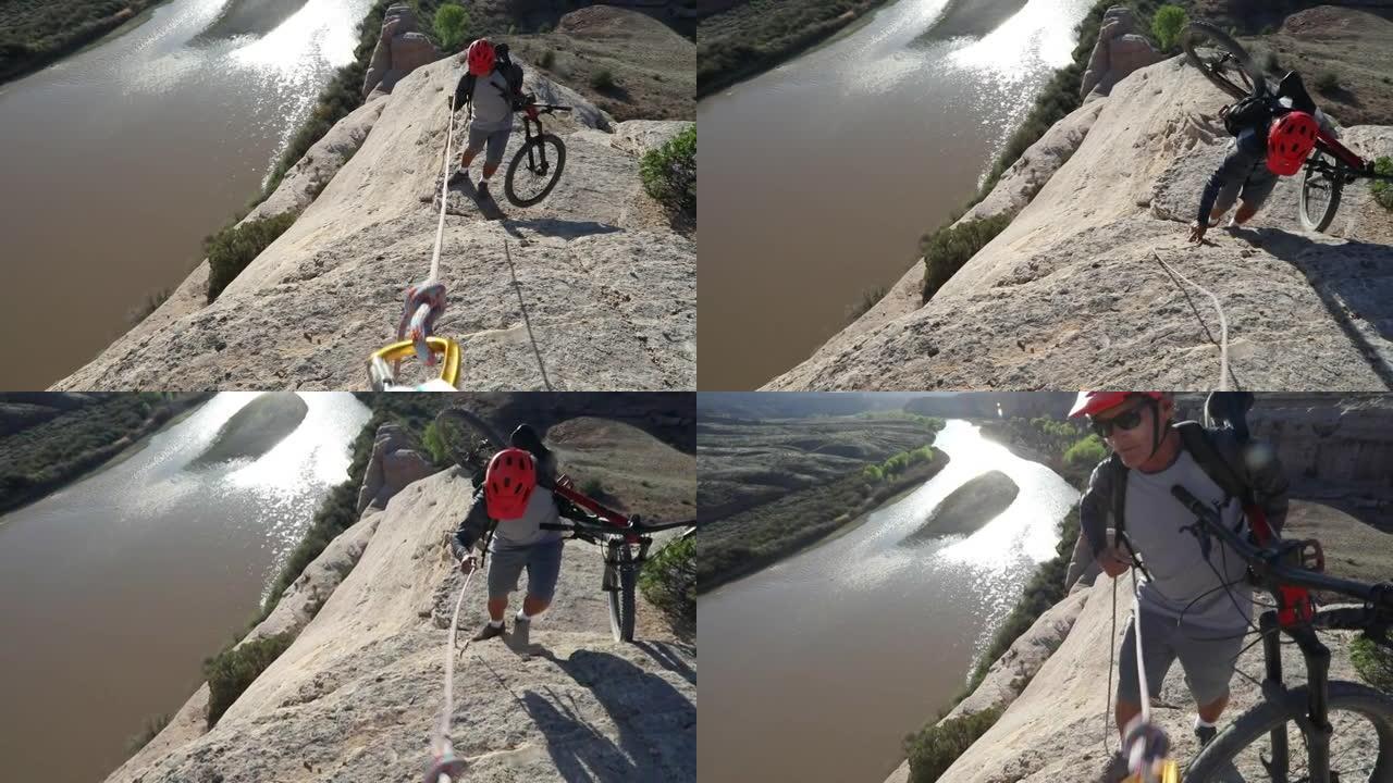 男性山地自行车手使用绳索帮助将峡谷边缘提升到河上