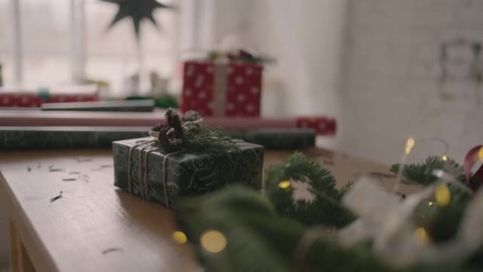 一份圣诞礼物站在一张有圣诞树和花环的木桌上。漂亮的圣诞礼物