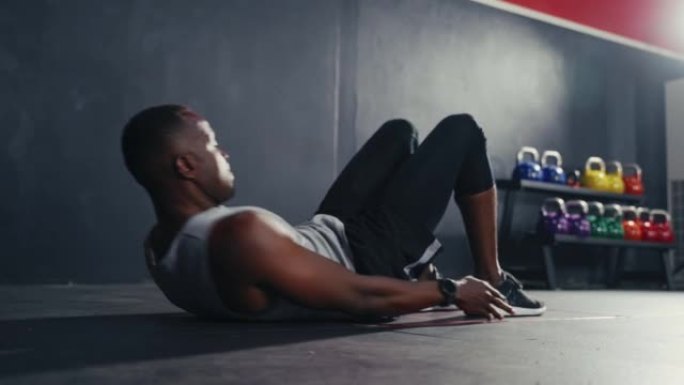 锻炼黑人男子在健身馆内摆动双腿进行健身锻炼和举重。身体锻炼力量和坚实的腹肌肌肉，促进身体健康。