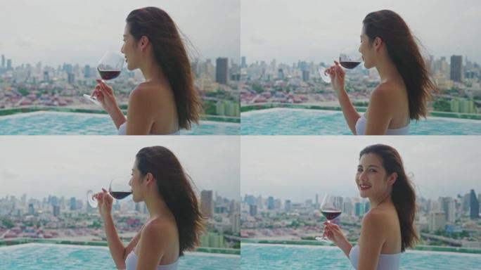 年轻漂亮的女人在豪华度假胜地的游泳池里喝杯红酒。