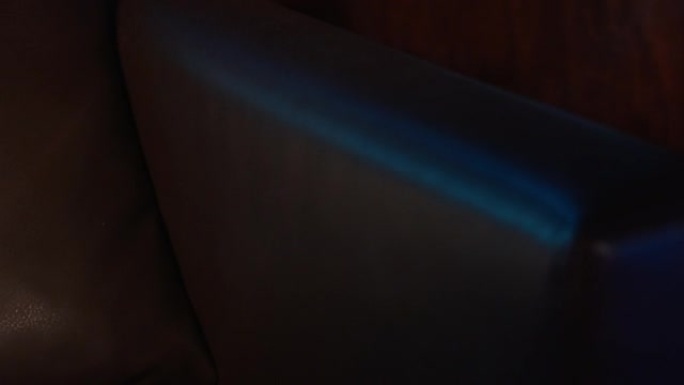 黑暗的客厅被蓝光照亮。看皮椅细节