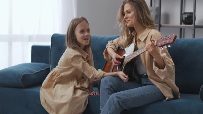 幸福的母女在一起弹吉他，女孩在为女人鼓掌