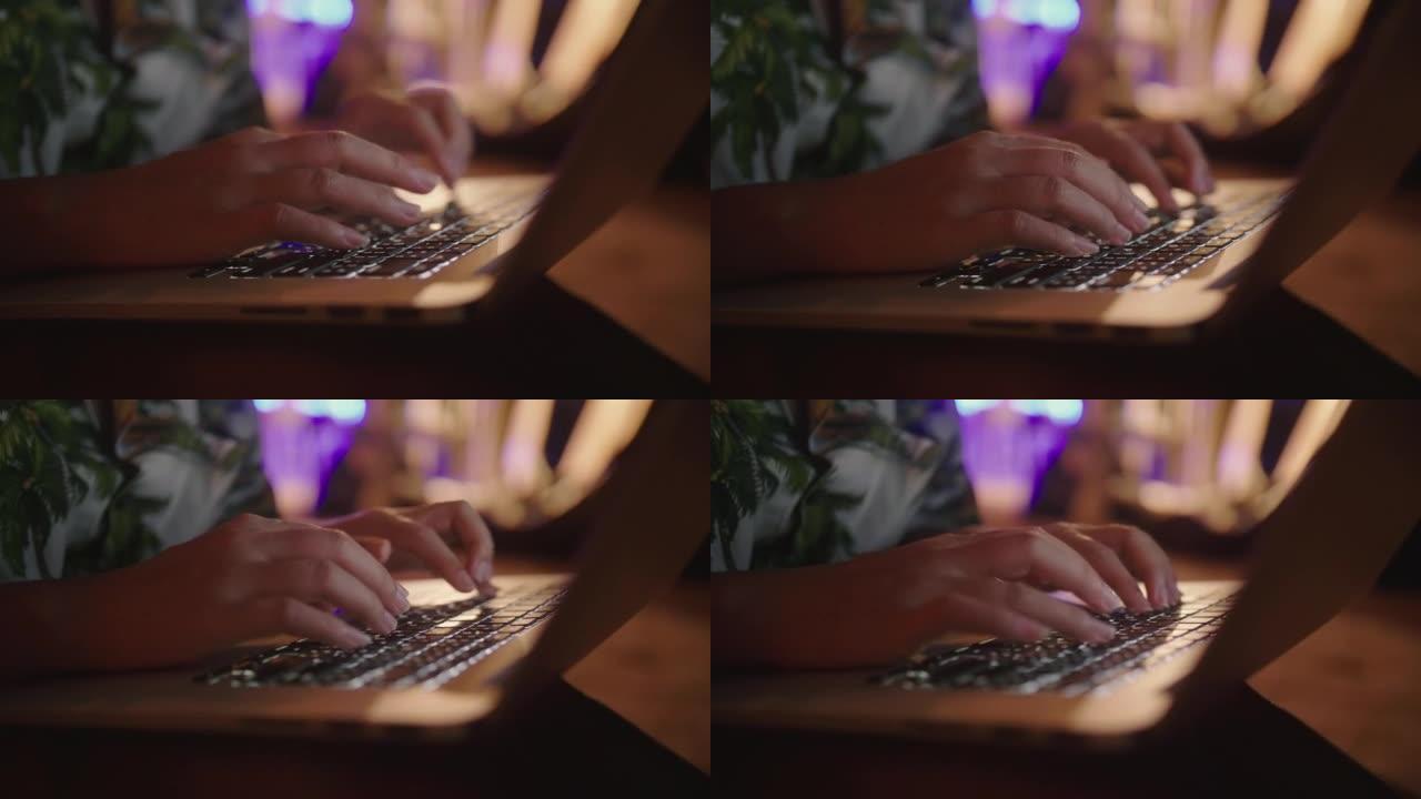 关闭女人的手在键盘上打字，并在晚上在海边度假时使用笔记本电脑触控板。