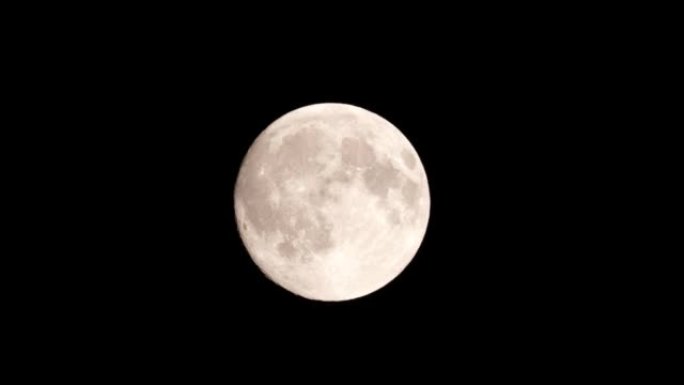 满月在深黑色的天空背景下，用很长的远摄镜头从地球表面拍摄。灰白色的月亮在晴朗的天空中发光。