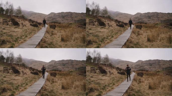 苏格兰高地开始下雨时，背着书包的人沿着木板路散步