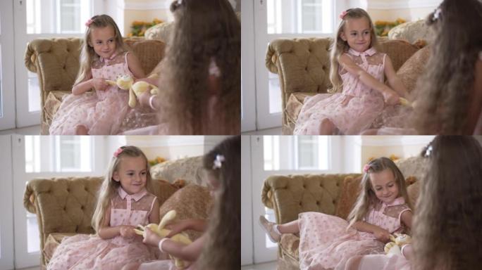 迷人可爱的女孩在家里和妹妹争夺玩具的肖像。漂亮的白人孩子在客厅里和兄弟姐妹在慢动作中争论。生活方式和