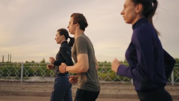 专业运动员跑步，三人准备马拉松，日落或日出时间慢跑