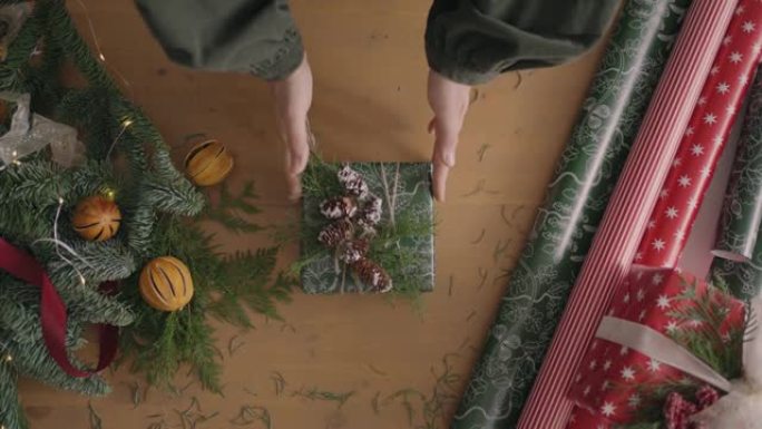自上而下的计划。完全可见带有装饰品的桌子。用手工纸包裹在木桌上的圣诞礼物。包扎胶带和绑弓。