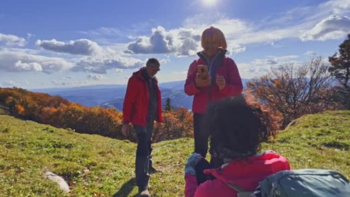 SLO MO徒步旅行者在阳光明媚的山顶上拍照