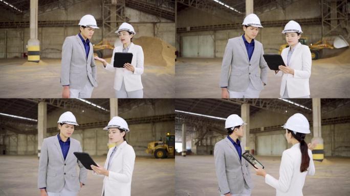 年轻的亚洲企业参观一家大型工厂，用平板电脑谈生意。