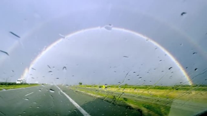 POV汽车驾驶。在雨中追逐彩虹