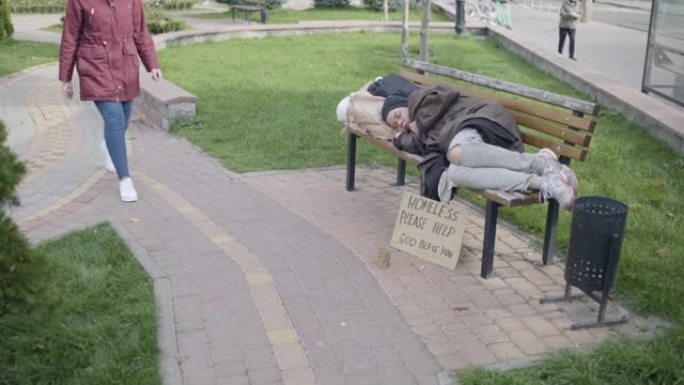 女陌生人向可怜的女人捐款，在长凳上睡觉，慈善事业