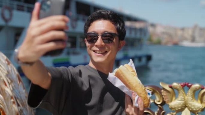 男性游客在旅行中享受吃街头美食时自拍
