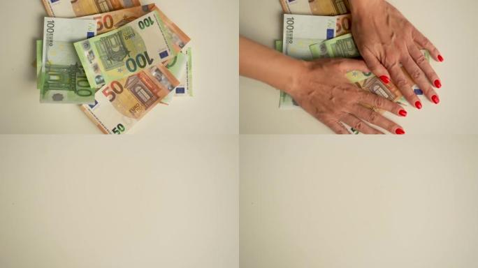 欧元纸币被扔在白色的桌子上。财富概念、家庭预算、在线业务和在线商务。赚大钱的概念。女人用两只手，拿走