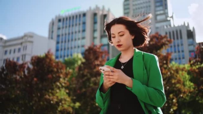亚洲女性在街上使用智能手机，查看社交媒体，阅读帖子和分享