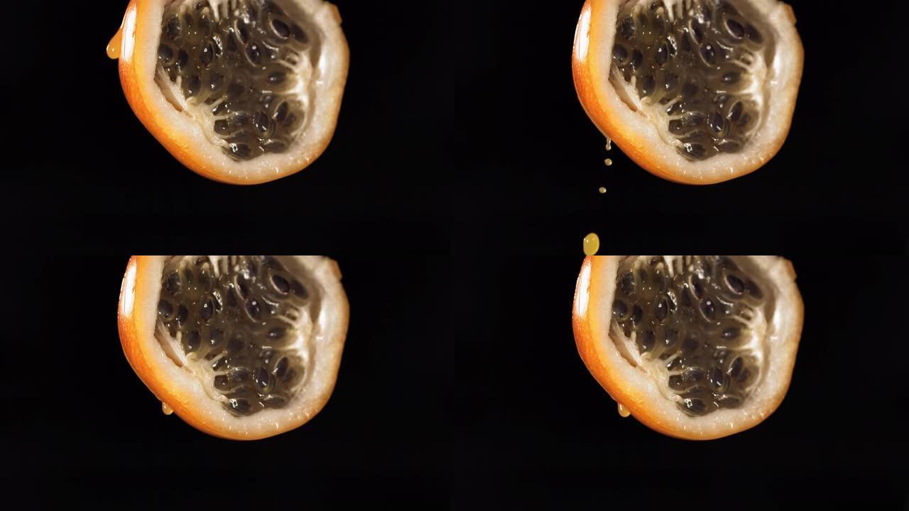 慢动作微距拍摄来自黑色背景中的一半的格拉纳迪拉汁的流动格拉纳迪拉汁