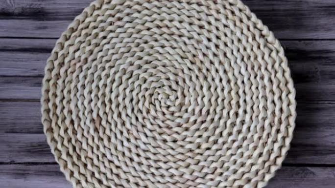 木制背景上的厨房用水葫芦纤维制成的圆形编织风信垫地毯。