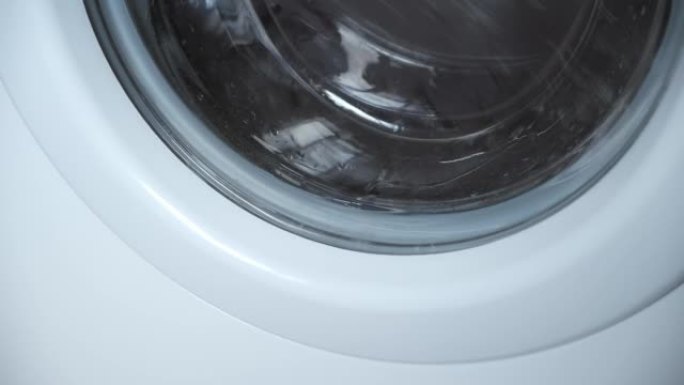 洗衣机拧干洗衣房的灰色床罩，特写窗口。