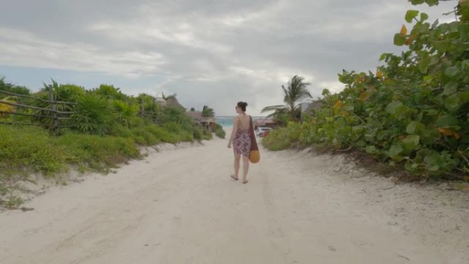 女人沿着丛林小路走向海滩