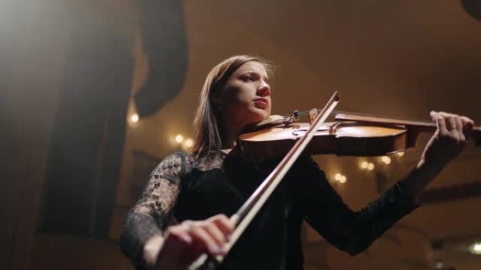 受启发的女音乐家在老歌剧院的现场演奏小提琴，音乐厅的小提琴手肖像