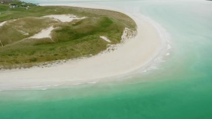 空中无人机在阴天拍摄了一个小半岛，靠近绿水青山的沙滩