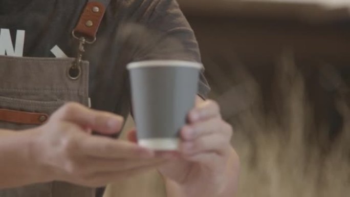 亚洲男子咖啡师在咖啡店里为顾客提供热咖啡杯