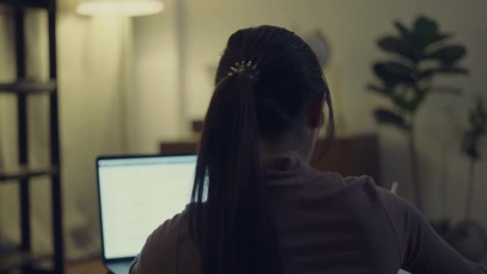 女人深夜在家用笔记本电脑和手机工作