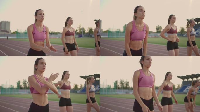 3名女子选手以慢动作准备在日落时在体育场进行长跑比赛