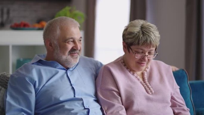 已婚的老年夫妇在客厅休息，老人和女人在一起聊天笑着，在室内拍摄肖像