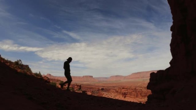 男子在美国西南部沙漠的费舍尔塔下徒步旅行