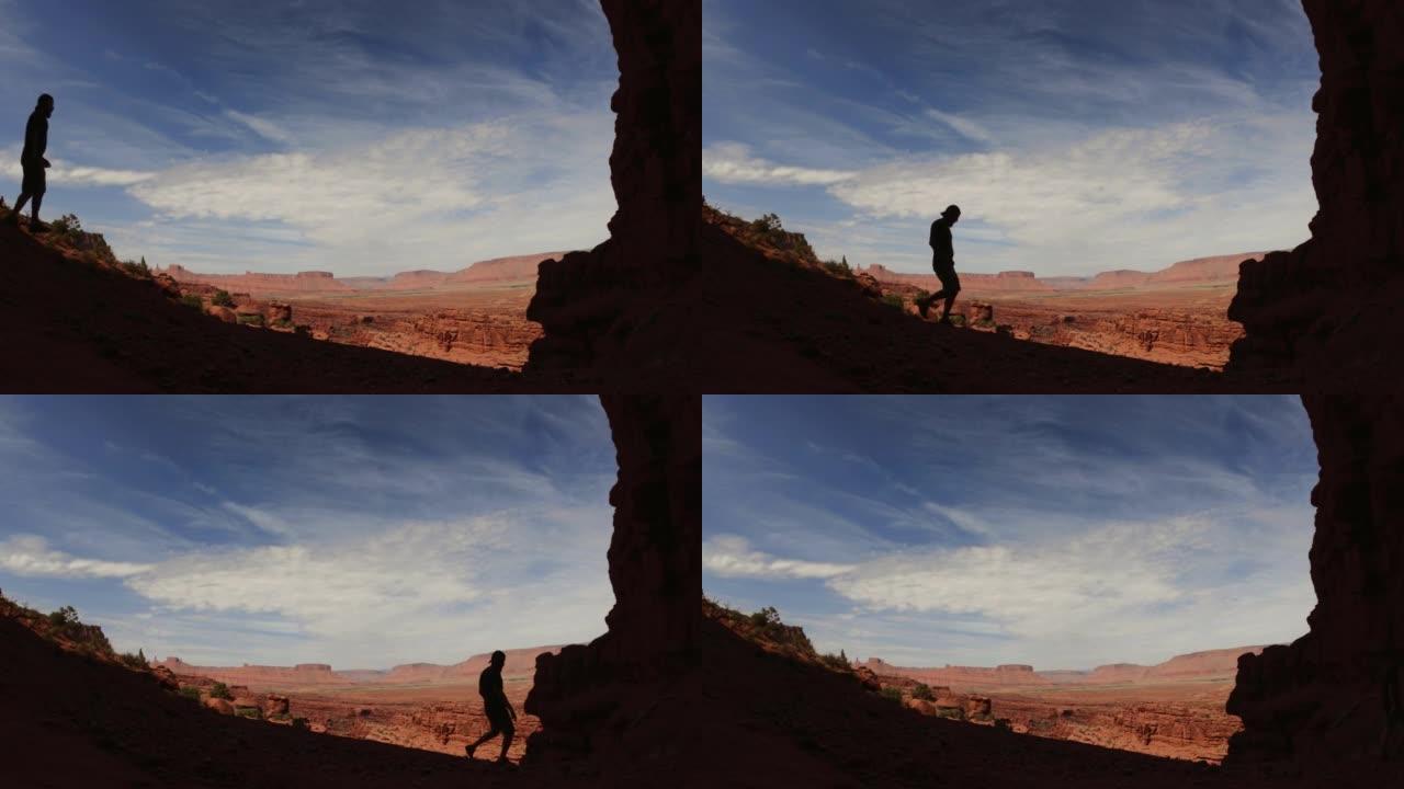 男子在美国西南部沙漠的费舍尔塔下徒步旅行