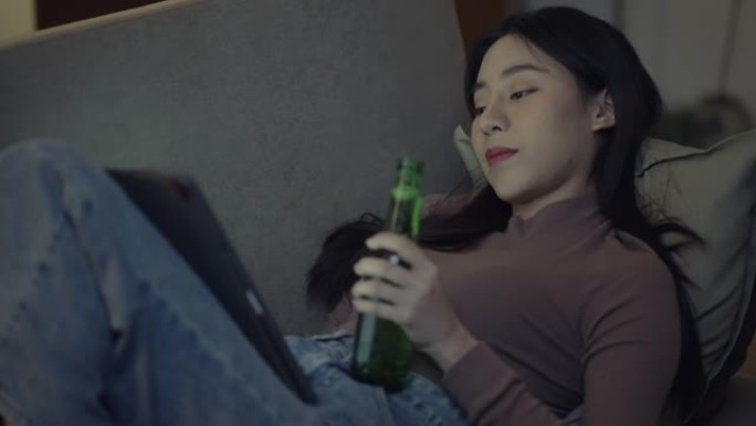 女人手持啤酒瓶使用数字平板电脑