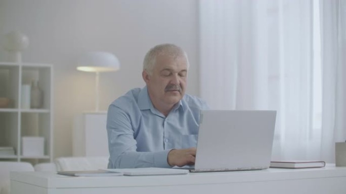 牙痛男子正在家庭办公室使用笔记本电脑，摩擦脸颊，牙齿或牙龈剧烈疼痛，工作日健康问题