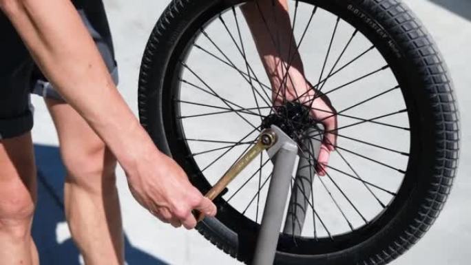 一个人用扳手拧开自行车上的轮子。