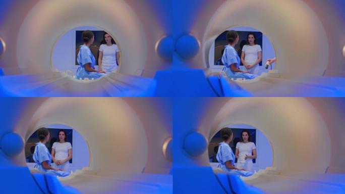DS女性患者坐在MRI机器的桌子上，与女性放射科技术人员交谈