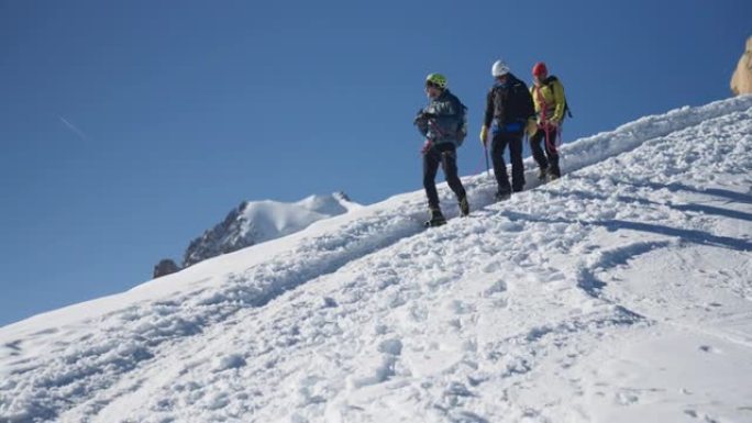 一队登山者沿着陡峭的山峰移动。使用绳索和攀爬设备