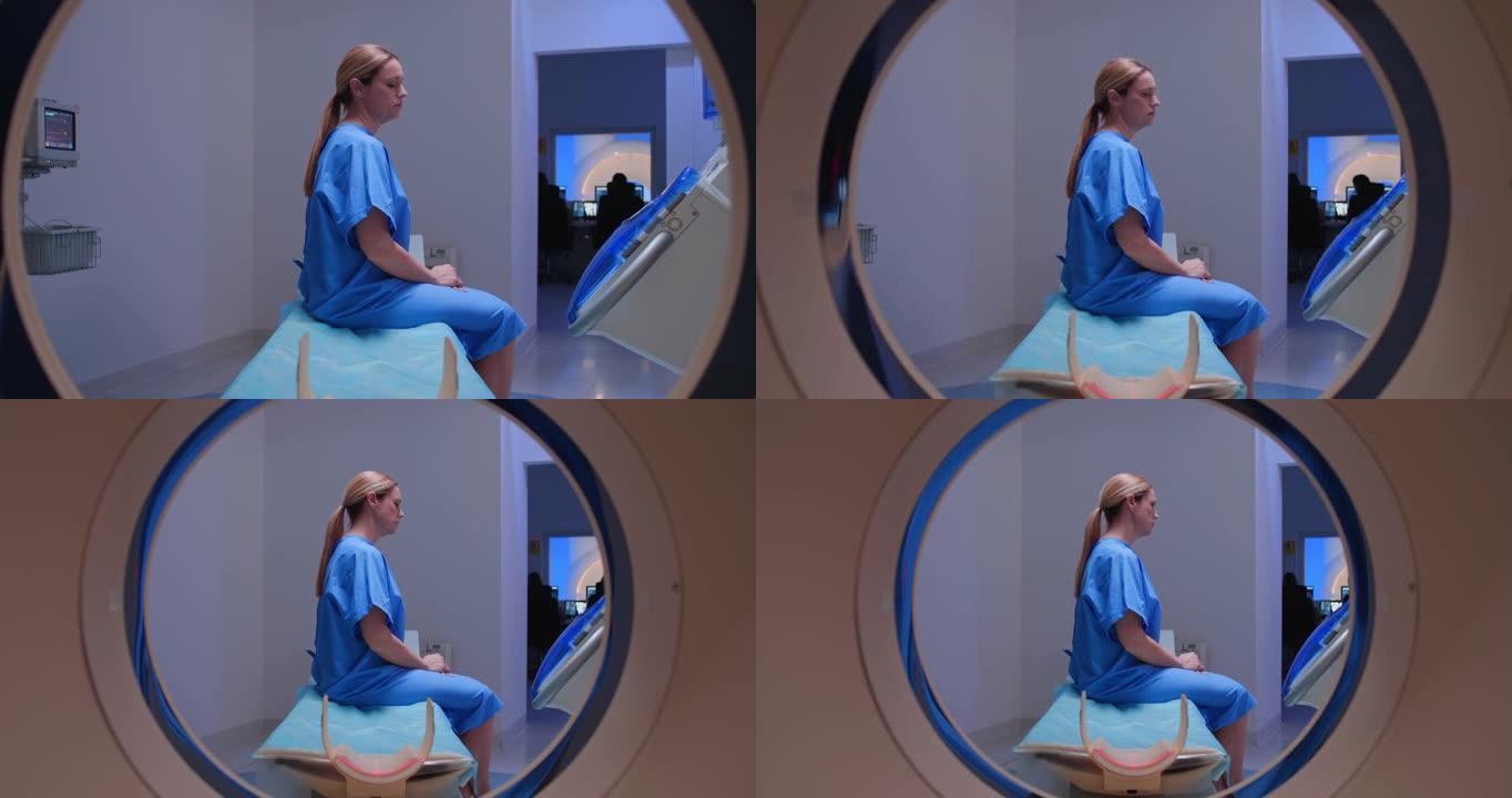 DS女患者坐在CAT扫描仪的桌子上，等待放射技术专家
