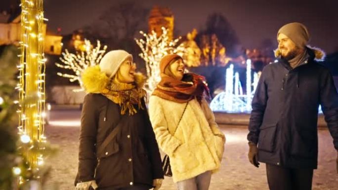 朋友在慢动作的下雪的圣诞节夜晚一起散步