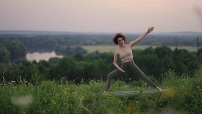 一名年轻女子通过在大自然的地毯上做瑜伽练习来保持平衡在背景中滑翔伞跳伞运动员正在慢动作飞行
