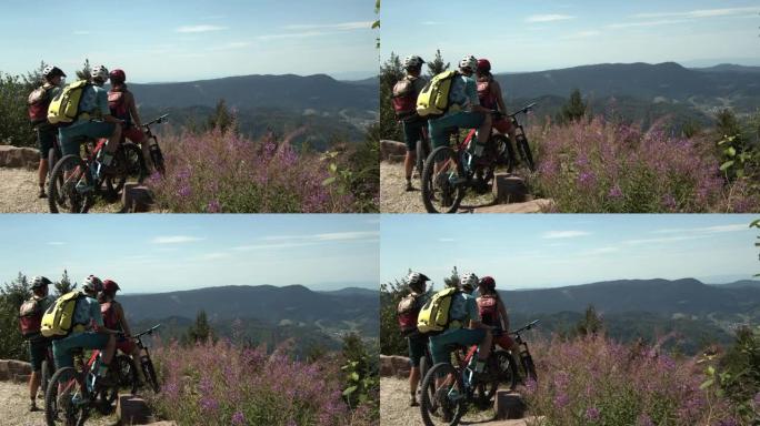 三个朋友在风景秀丽的监视下从下坡的山地自行车冒险中休息一下
