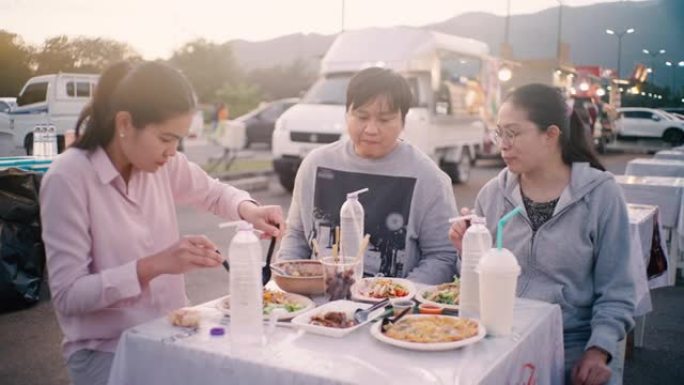 亚洲朋友晚上在the Foot Truck City聚会共进晚餐，分享食物并享受乐趣。