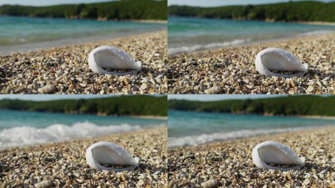 被丢弃的帽子埋在圆石滩上。旅游污染