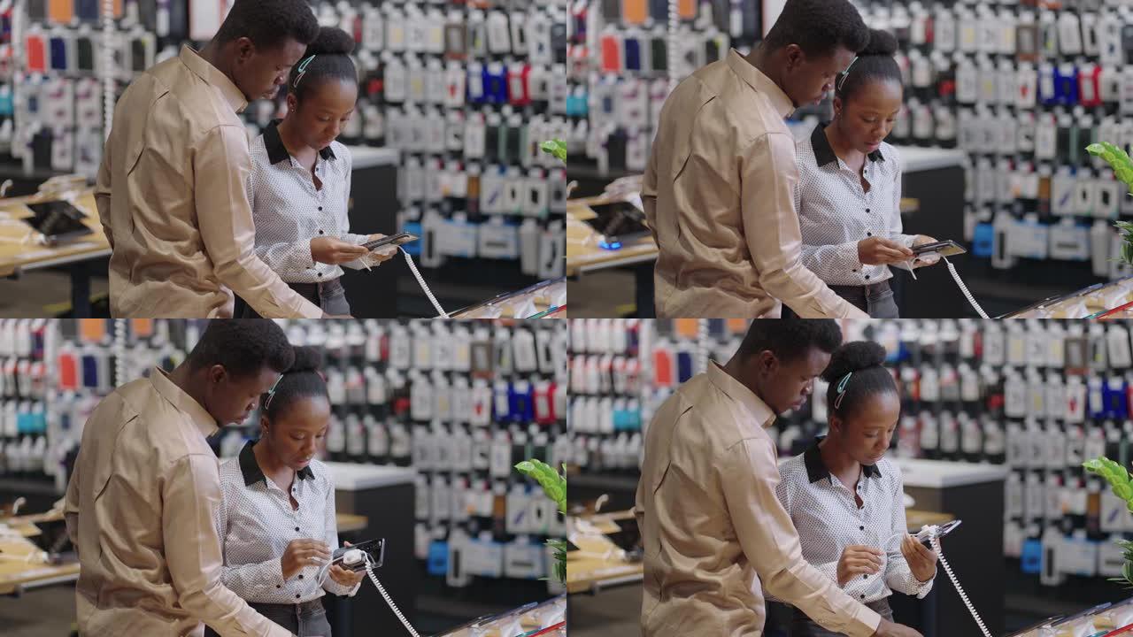 美国黑人男子正在帮助女友选择手机，一对正在数字设备商店购物