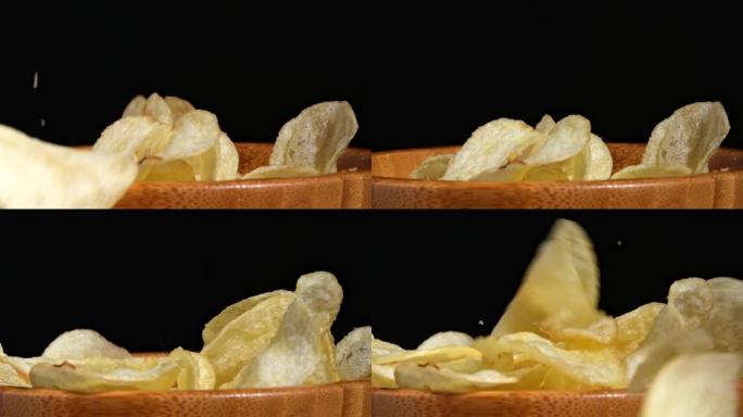 封闭的薯条或手工油炸的金薯片漂浮在空中，慢动作在木盘上飞行。快餐背景。零食掉进碗里