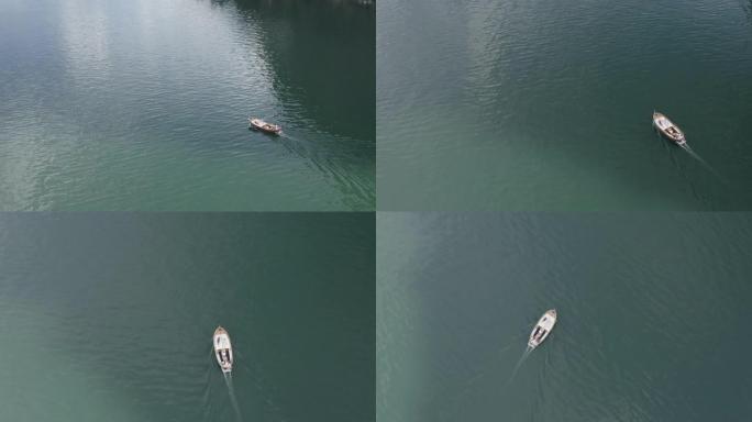 空中无人机在绿蓝水的湖上拍摄了一艘船