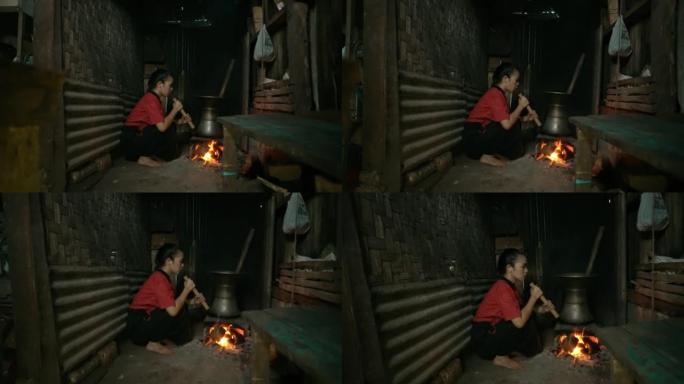 亚洲盲人妇女做饭时用一块竹制鼓风机吹老式火炉